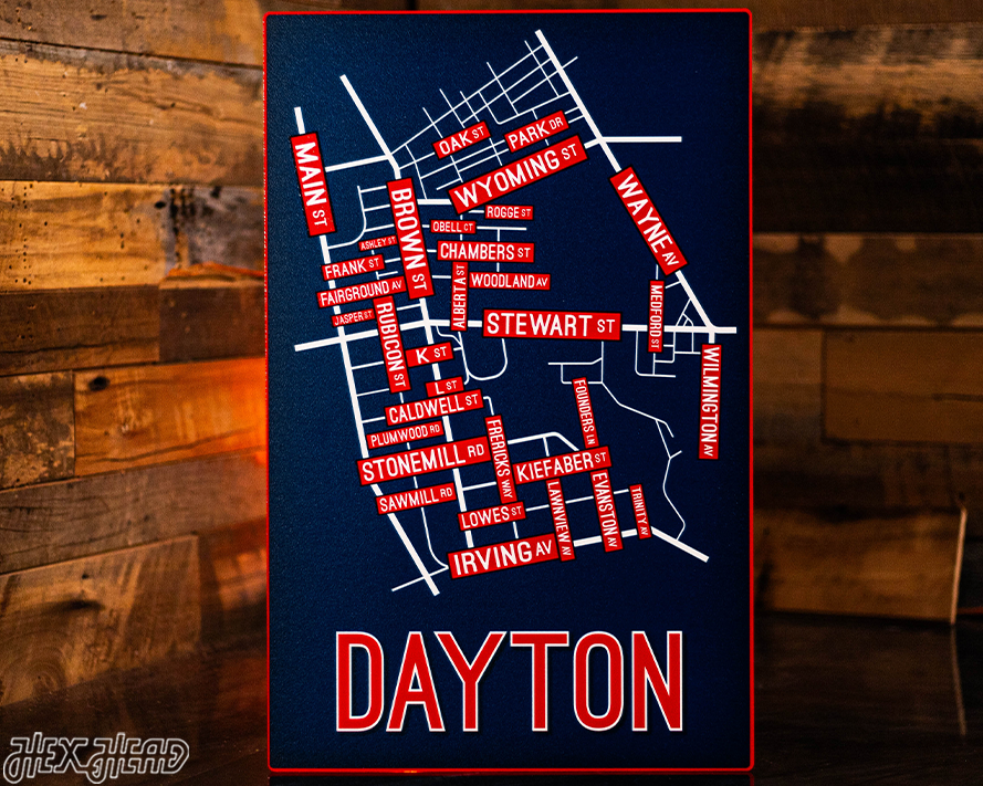 Map of Dayton with street names on a dark blue background, against a wooden wall.